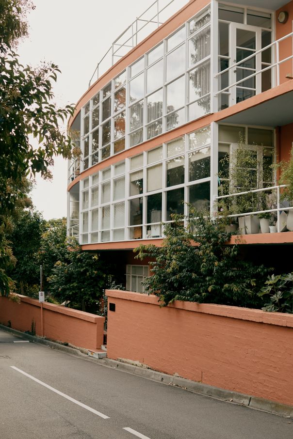 A photo of Caringal flats on Tahara Road that are three storeys with large expansive windows and a peach coloured building render. 
