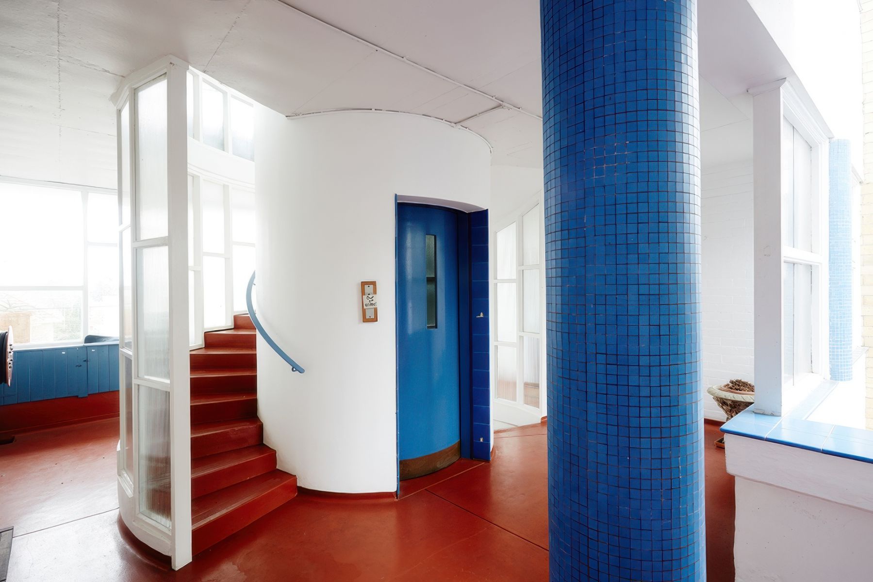 The interior of the Moonbria complex on Mathoura Road in Toorak. Depicts interior with red floors, a stairway and blue tiled pillars. 