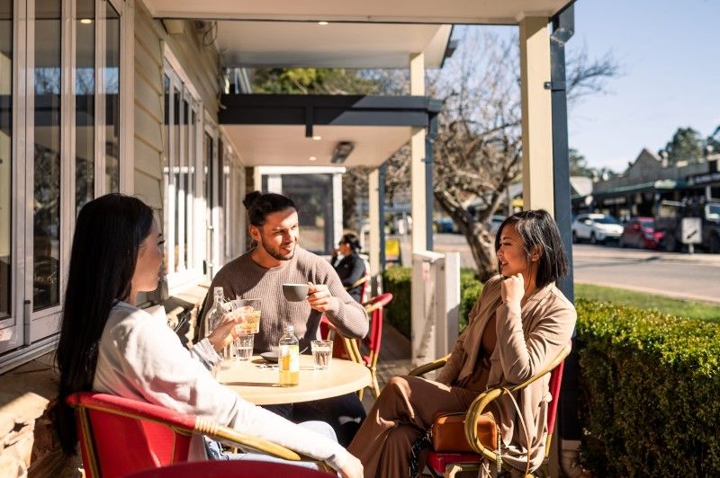 Photo of people enjoying a coffee at a cafe on a sunny day to represent community at a tiny town