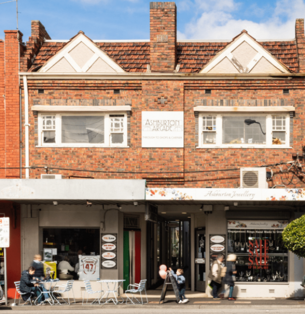 Photo showing an old heritage building in Ashburton and people on the sidewalk enjoying a sunny day.